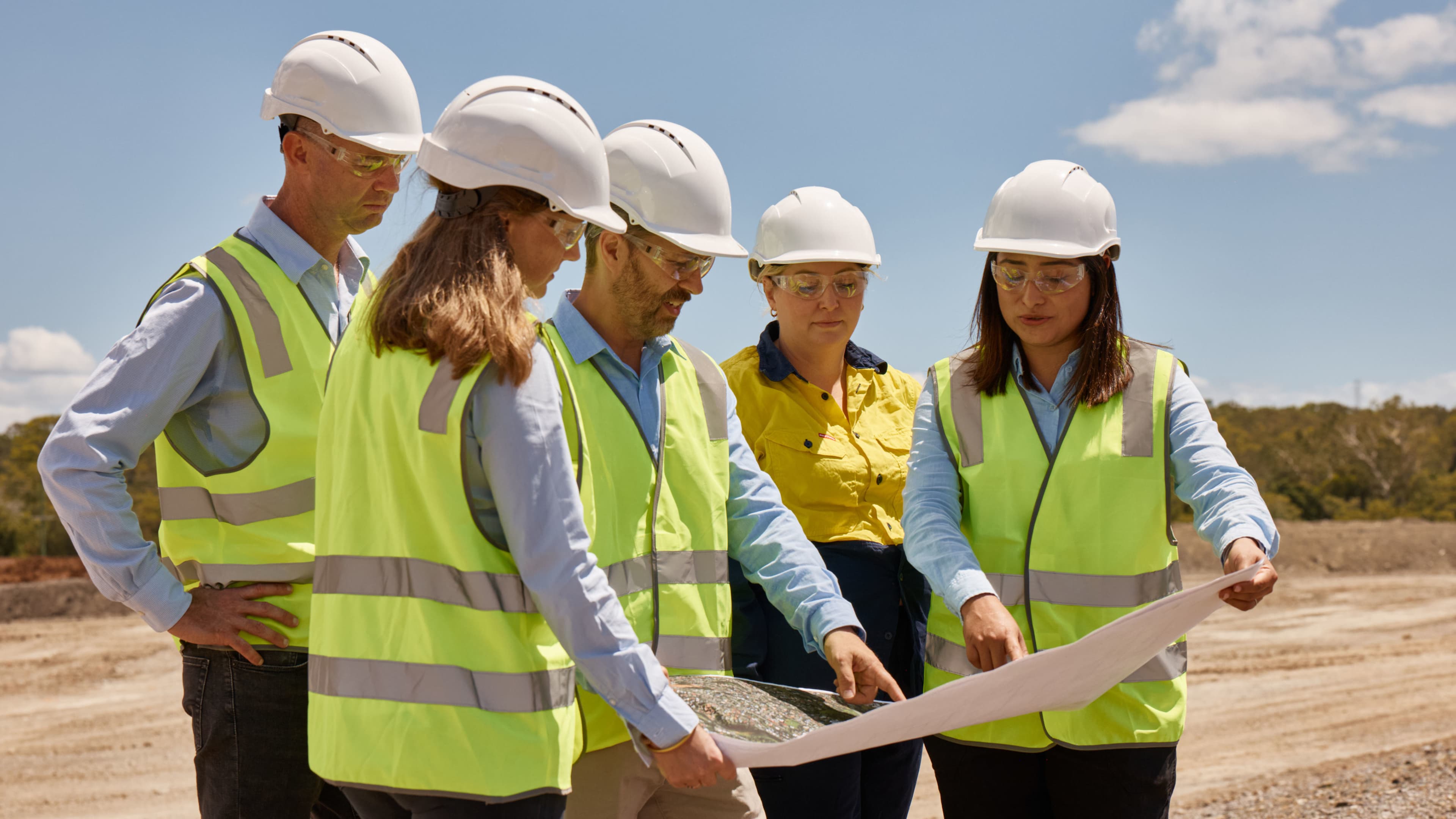 Five GIICA construction workers pointing at plans