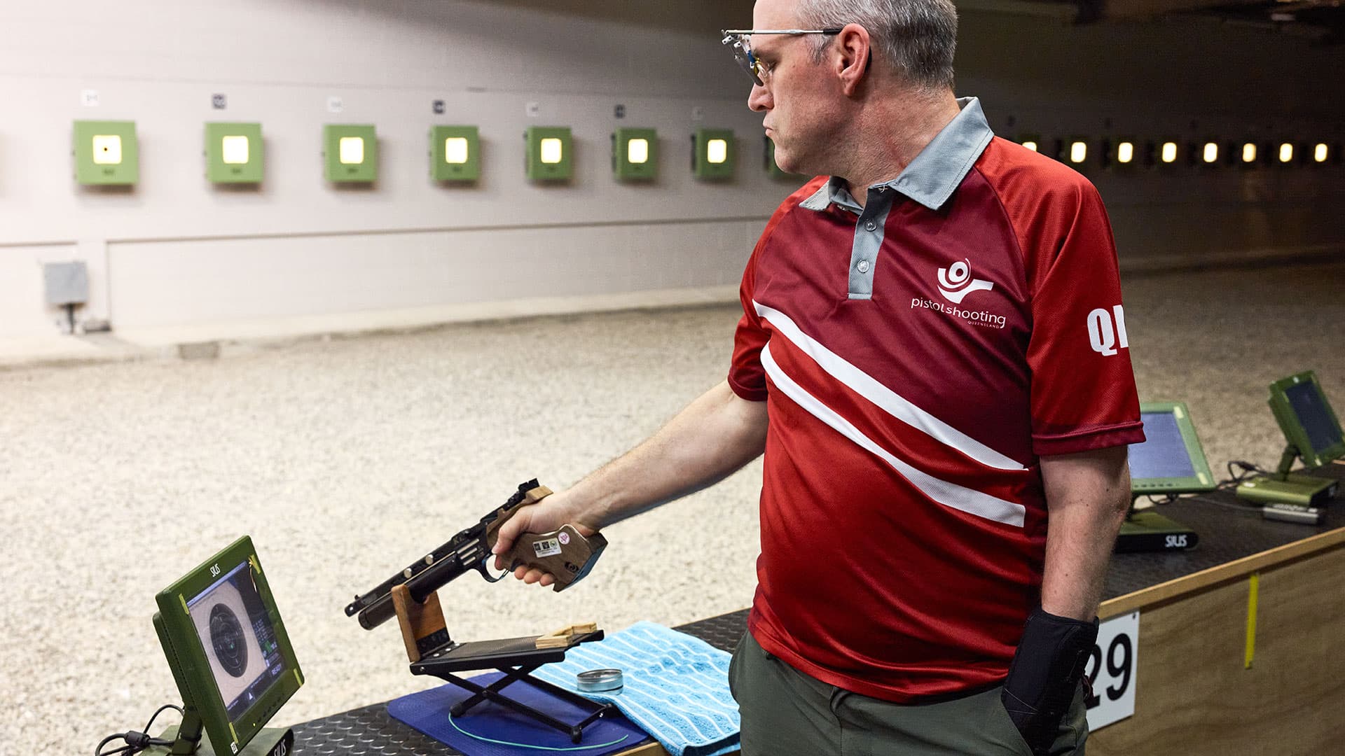 A person holds a pistol at an indoor shooting range