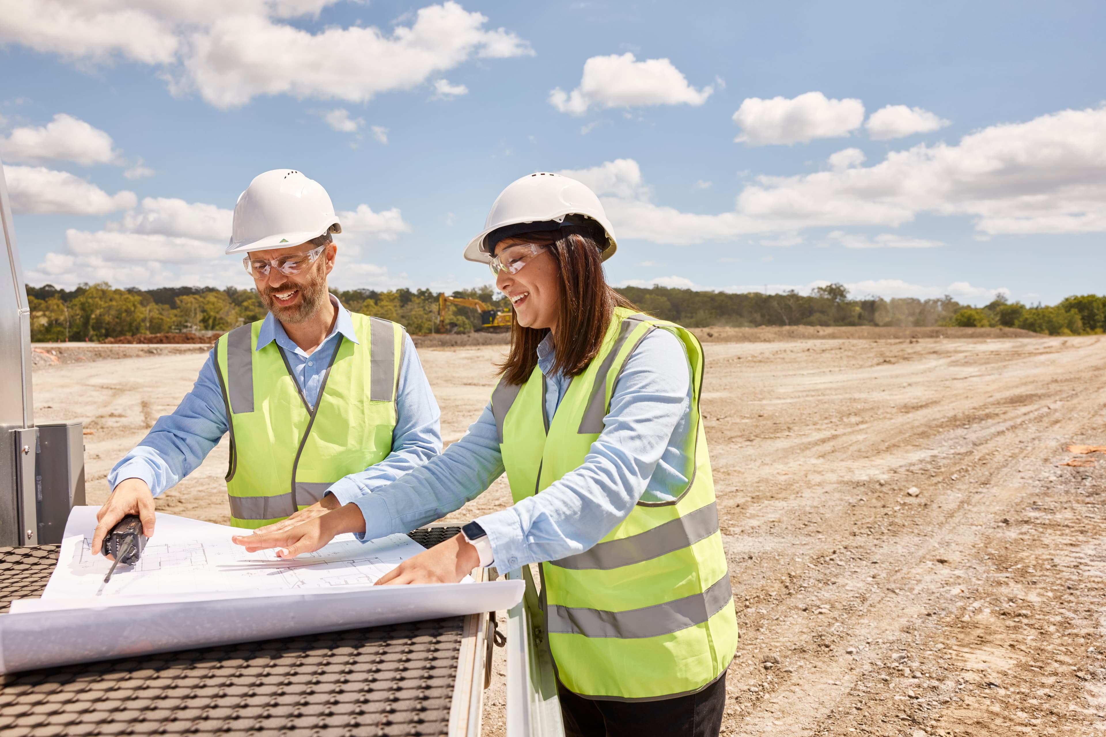 Construction workers looking at plans on a cleared worksite